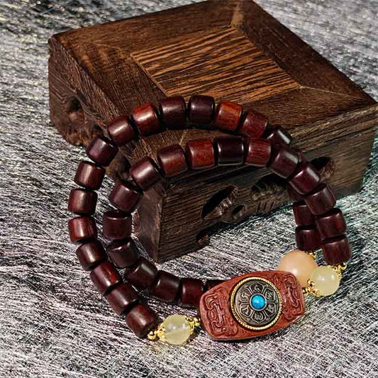 Handmade dark ebony wood double strand bracelet featuring an intricately inlaid fortune disk charm, a meaningful gift for luck and spiritual protection.