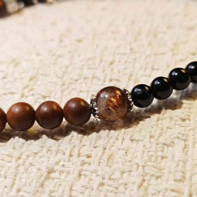 A handcrafted bracelet featuring natural wood beads, black onyx stones, and a warm amber center bead for a balanced and minimalist style