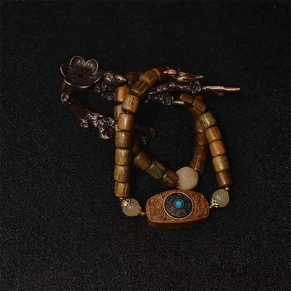 A double strand luck and protection bracelet made from genuine green sandalwood. Features a central handmade fortune disk charm with intricate wood inlay work.