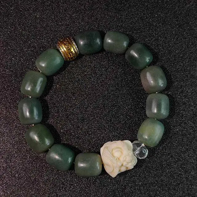 A handmade green Bodhi seed bracelet with a detailed awakening lion charm, symbolizing protection and mindfulness. Natural stones and copper accents on a braided cord.