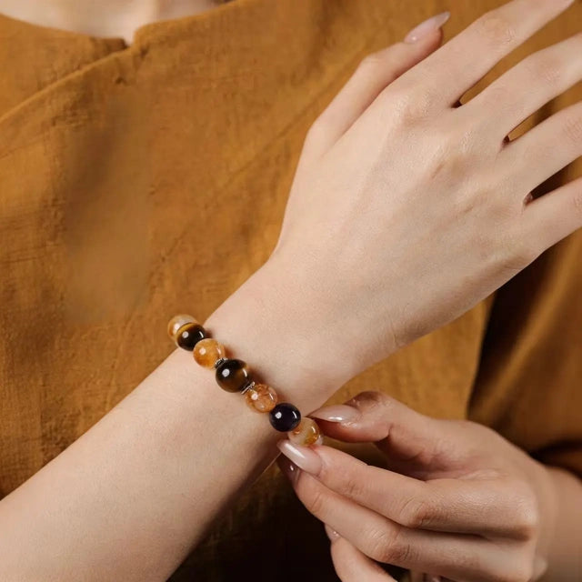 Front view of a premium natural gemstone beaded bracelet on a woman's wrist, featuring gold rutilated quartz and amethyst.