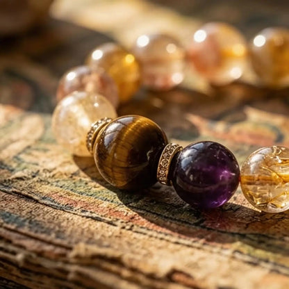 Extreme macro close-up of a tiger's eye and amethyst bead with textured metal spacers, showing the internal golden rutiles in the quartz crystal.