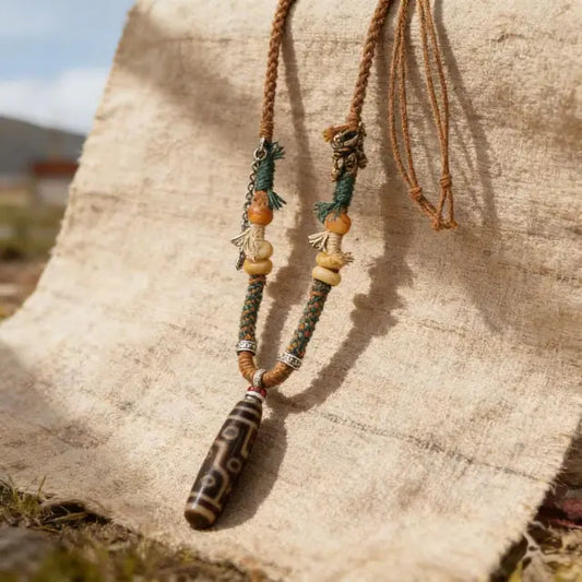 Tibetan Dzi bead necklace in natural sunlight, handmade braided cord with wooden accents, boho spiritual jewelry outdoor scene